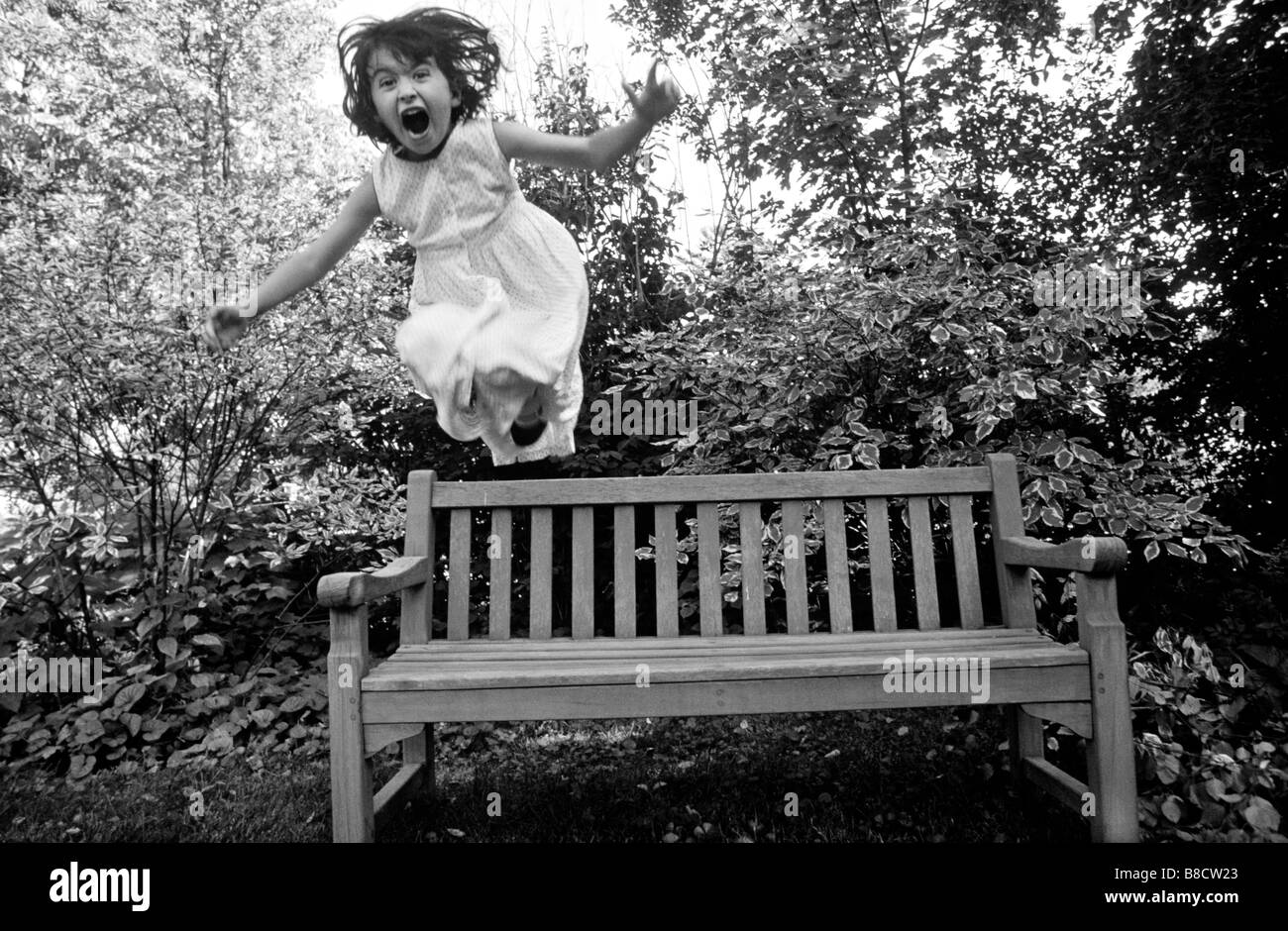 Girl Jumps f Park Bench Stock Photo