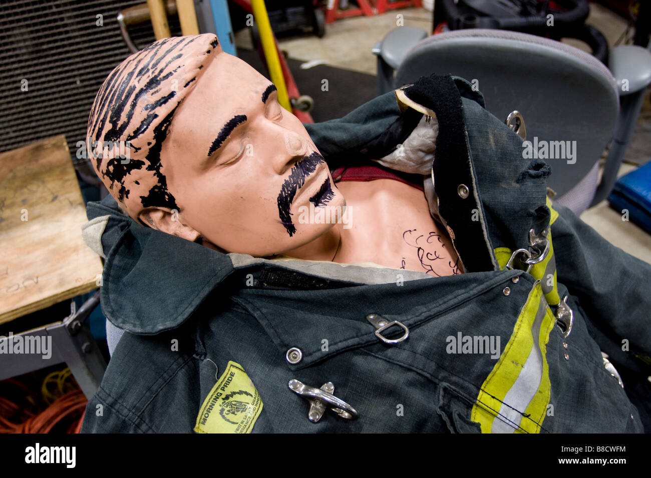 A firefighter training dummy with humorous mustache and hair drawn on wearing a protective fire suit Stock Photo