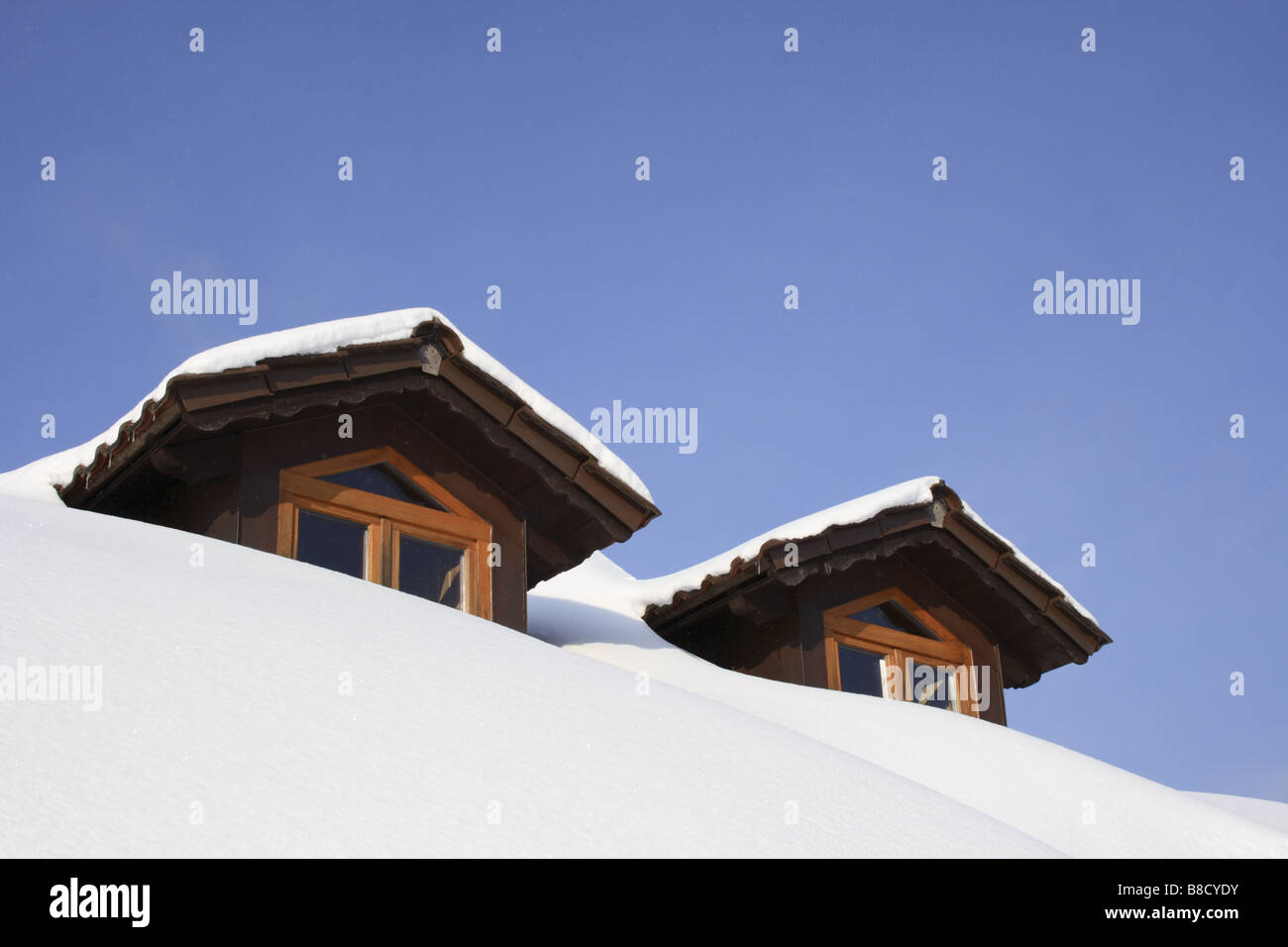 two attic windows on roof of Bavarian House, covered by snow in winter ...