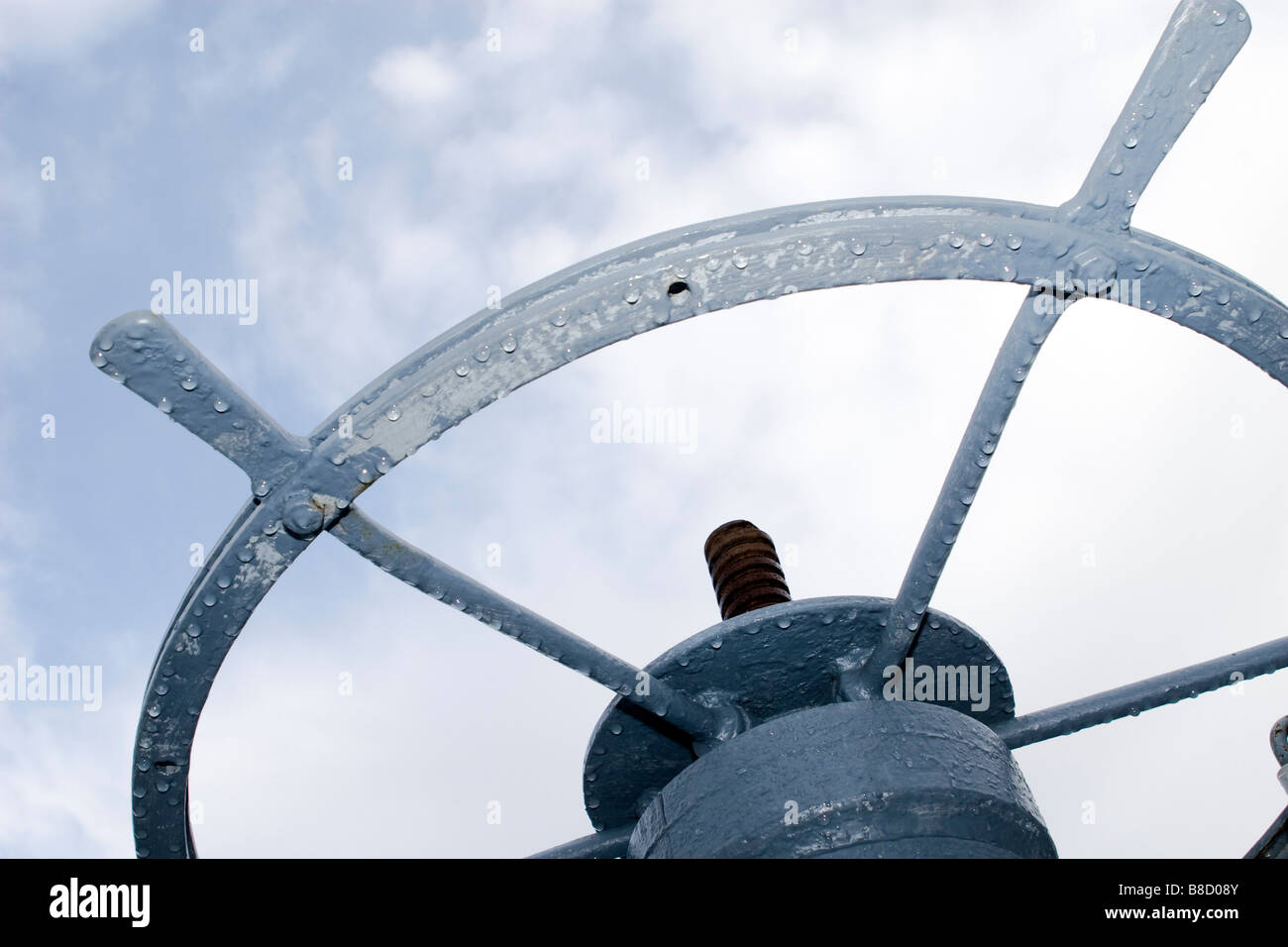 Wheel of the hand operated sluice over blue sky with clouds. Stock Photo