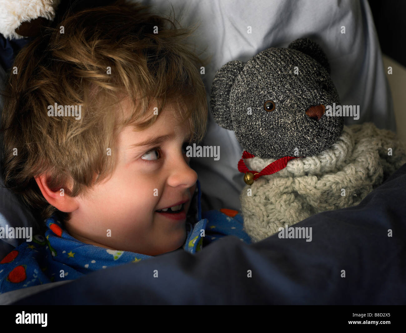 boy laying in bed looking at his teddy bear smiling Stock Photo - Alamy