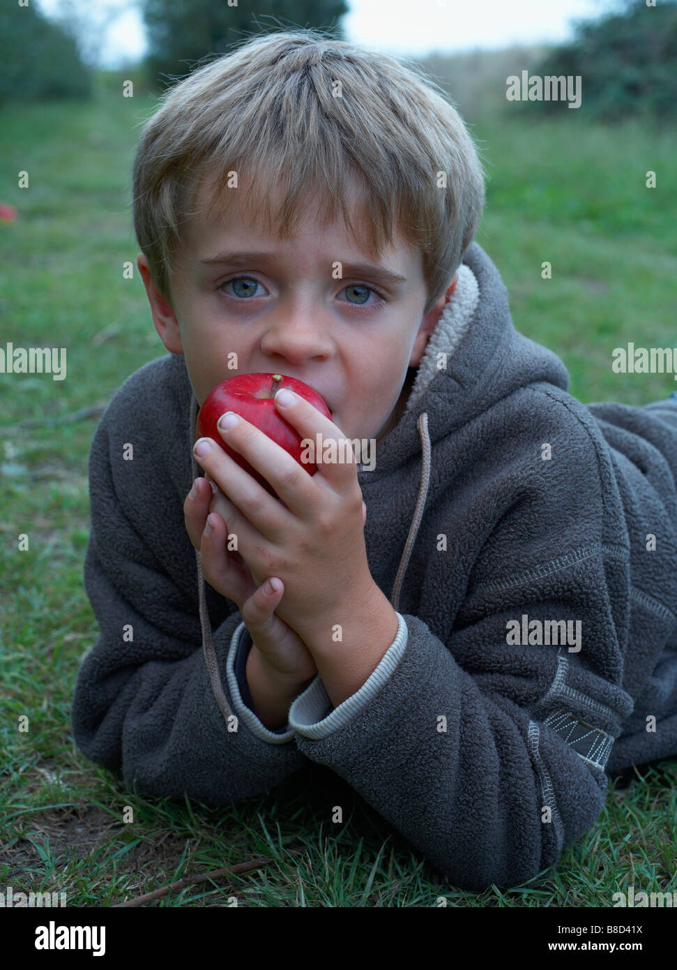 Boy 8 child laying on floor eating apple Stock Photo