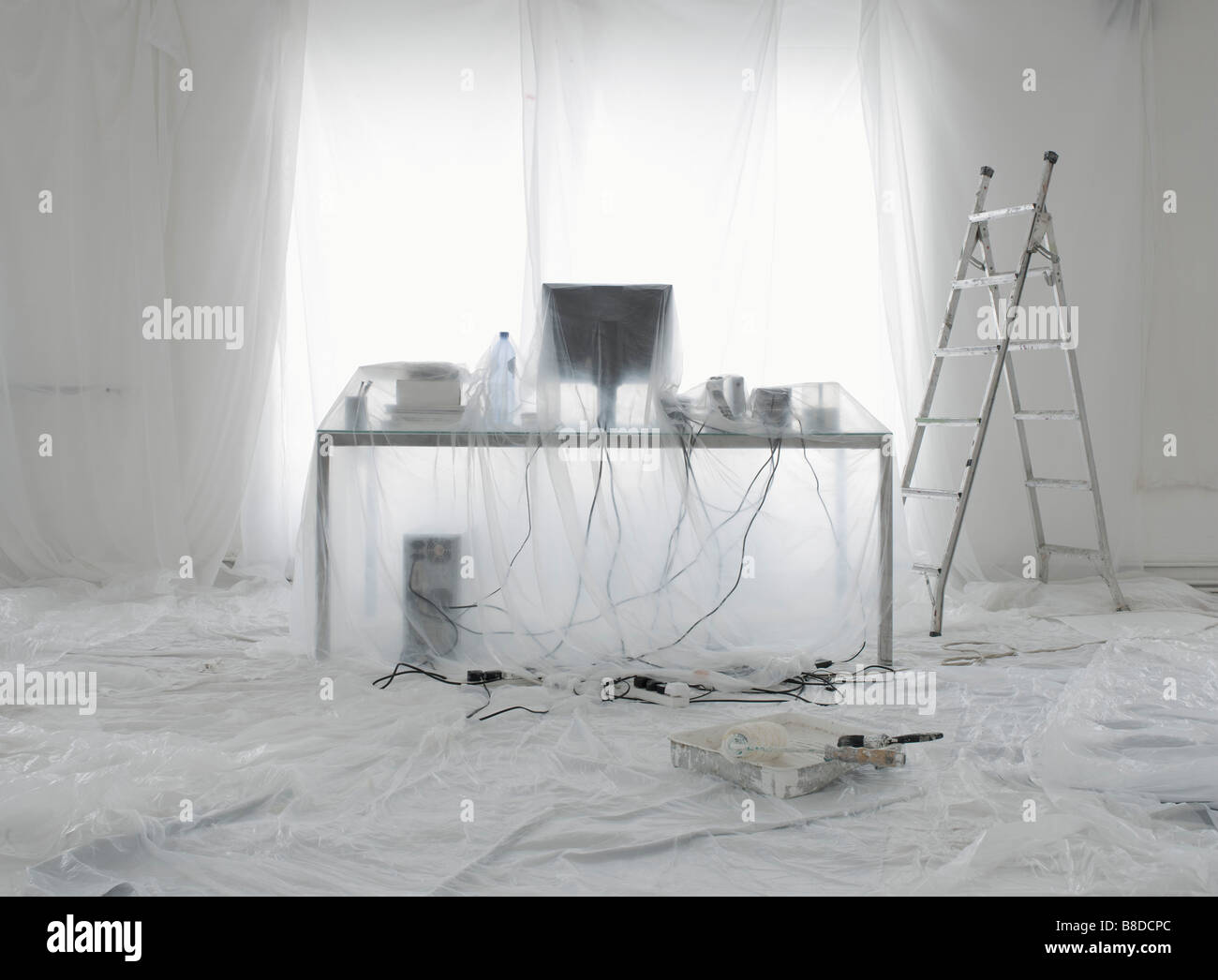 Desk and computer covered in transparent dust sheets in preparation for