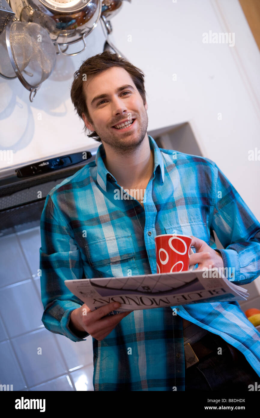 attractive male model reads the morning paper and drinking tea, coffee