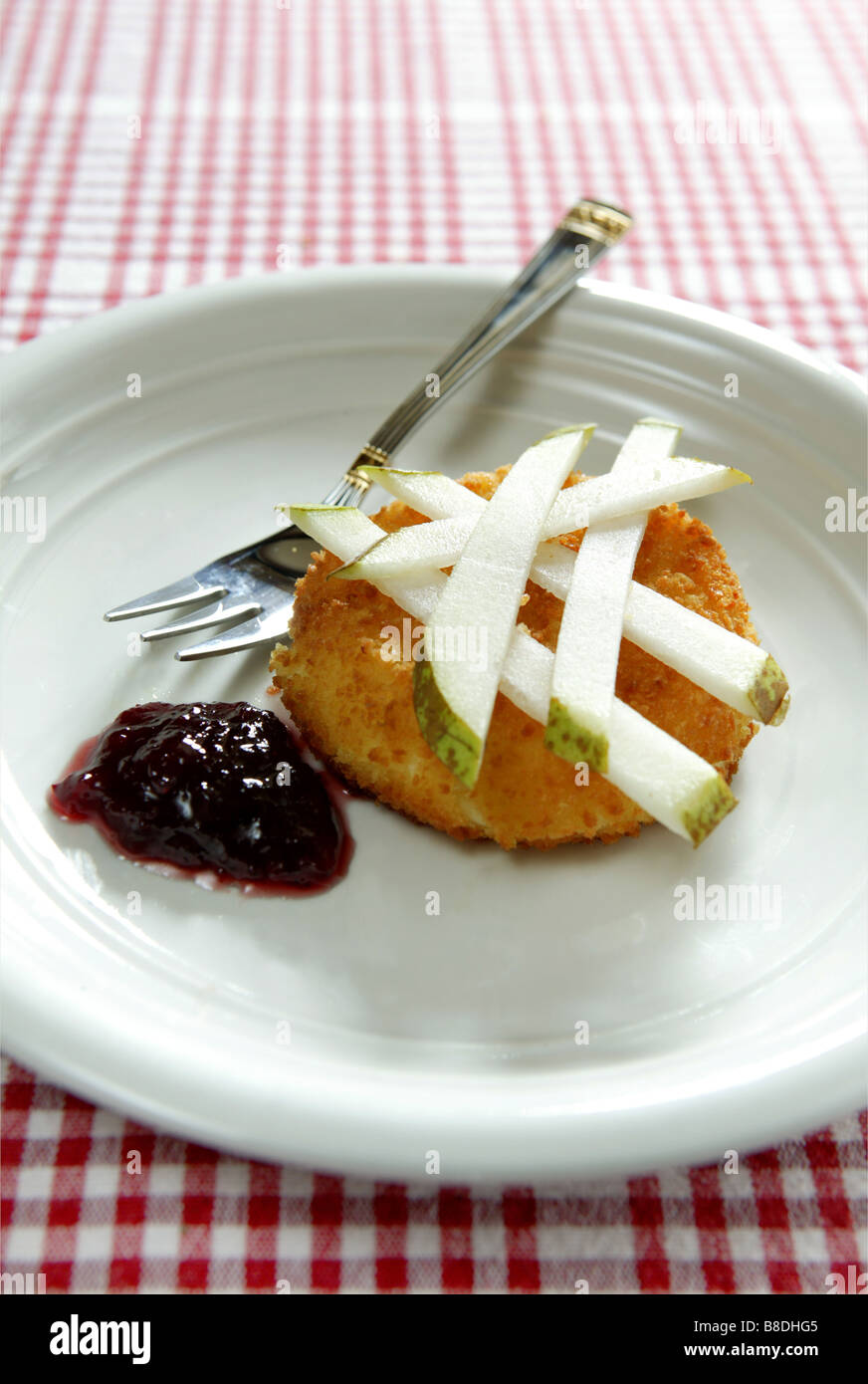 a low view of lunch including a small grilled cheese placed on a white plate with strips of pear on top. Stock Photo