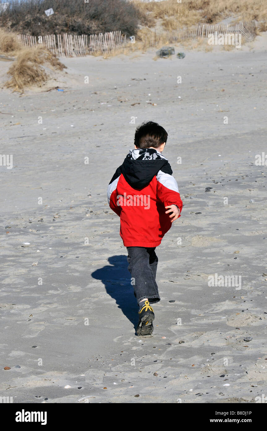 young boy in red jacjket running on Salty brine beach in Rhode Island. Stock Photo