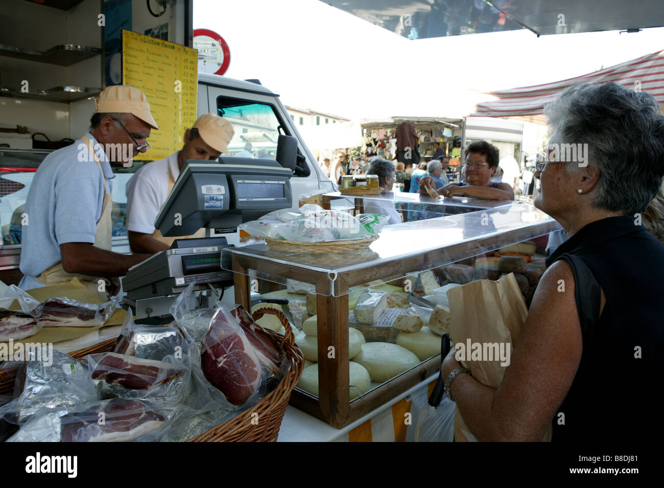 Landscape horizontal format Italian village market stall selling numerous cheeses and meats elderly retired old individuals Stock Photo