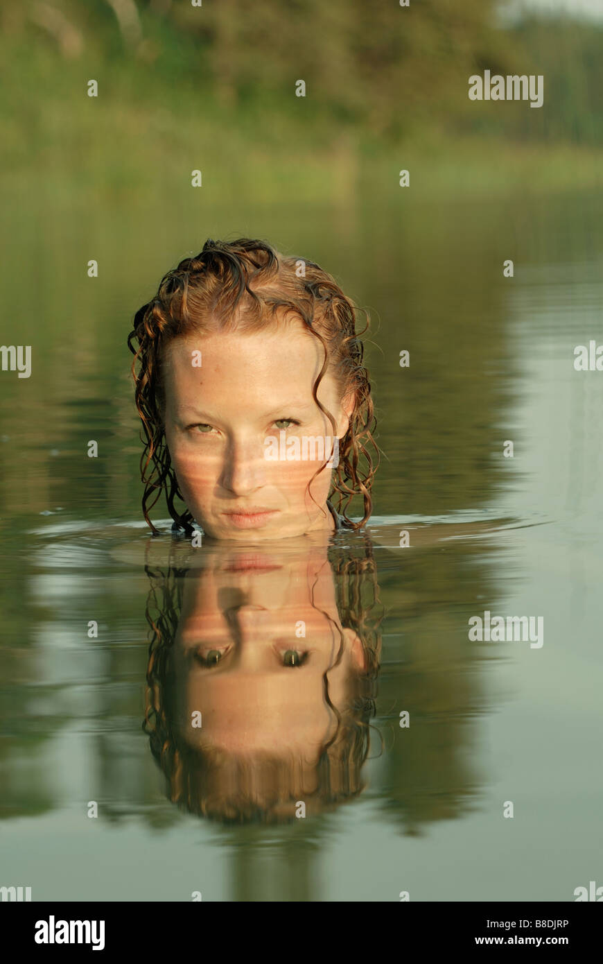 Woman in lake with face reflected in water, Lake Katherine, Riding Mountain National Park, Manitoba, Canada Stock Photo
