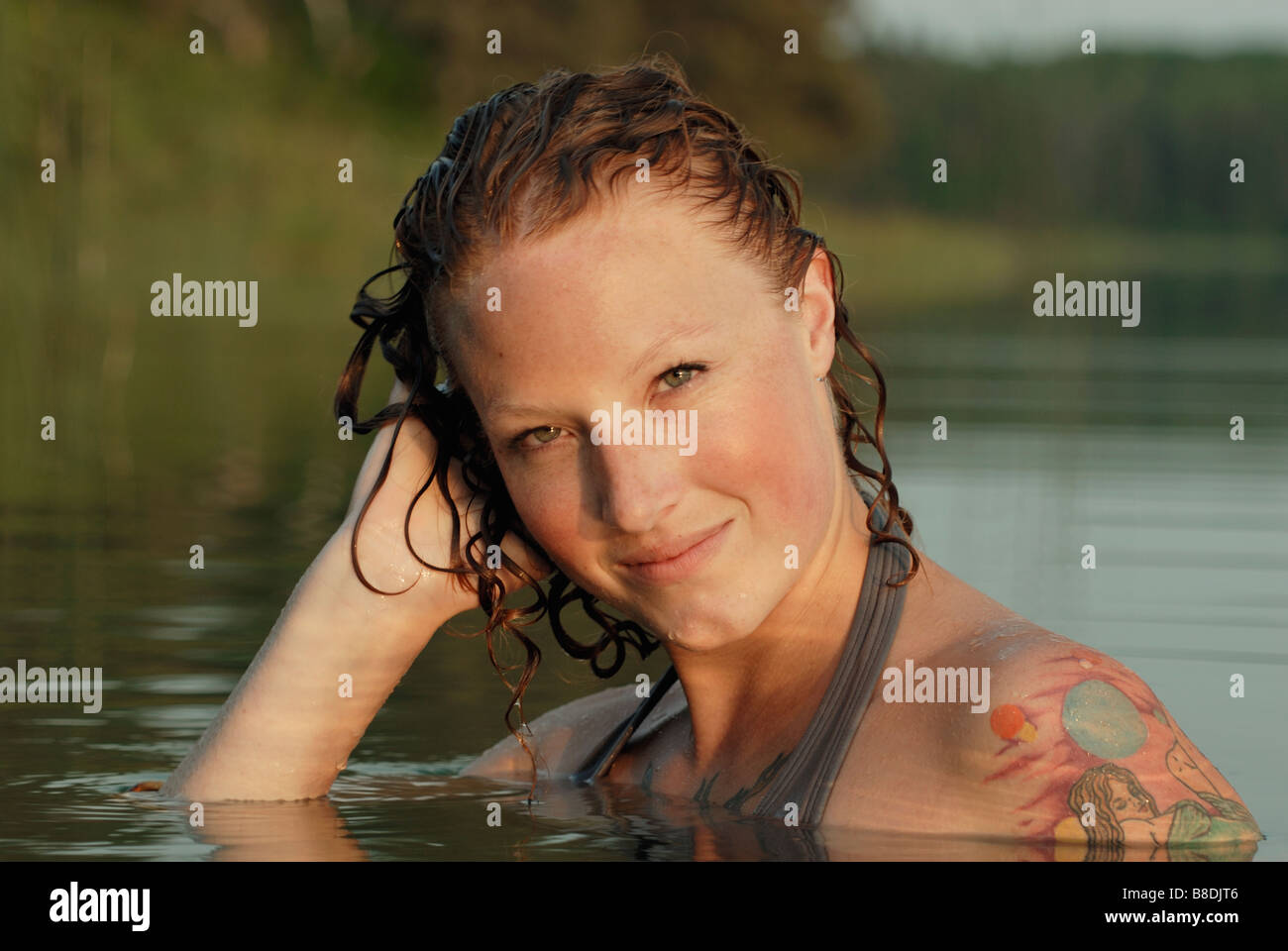 Woman with hand to wet head in lake, Lake Katherine, Riding Mountain National Park, Manitoba, Canada Stock Photo