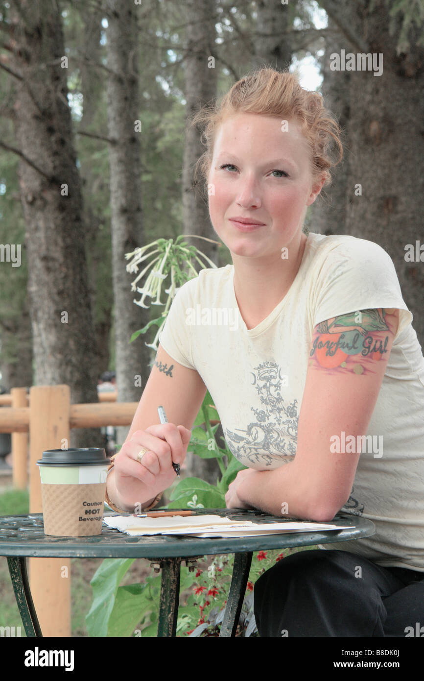 Woman at outdoor restaurant, corn-based compostable coffee cup, Wasagaming, Riding Mountain National Park, Manitoba, Canada Stock Photo