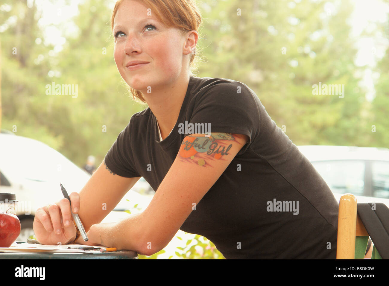Woman seated at table outdoors, writing, Wasagaming, Riding Mountain National Park, Manitoba, Canada Stock Photo
