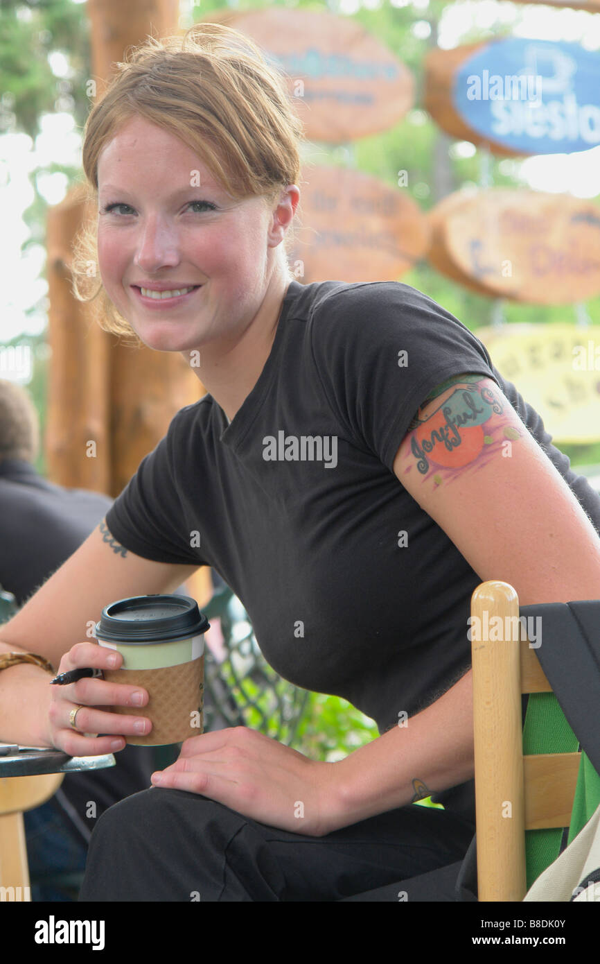 Woman at outdoor restaurant holding corn-based compostable coffee cup, Wasagaming Riding Mountain National Park Manitoba Canada Stock Photo