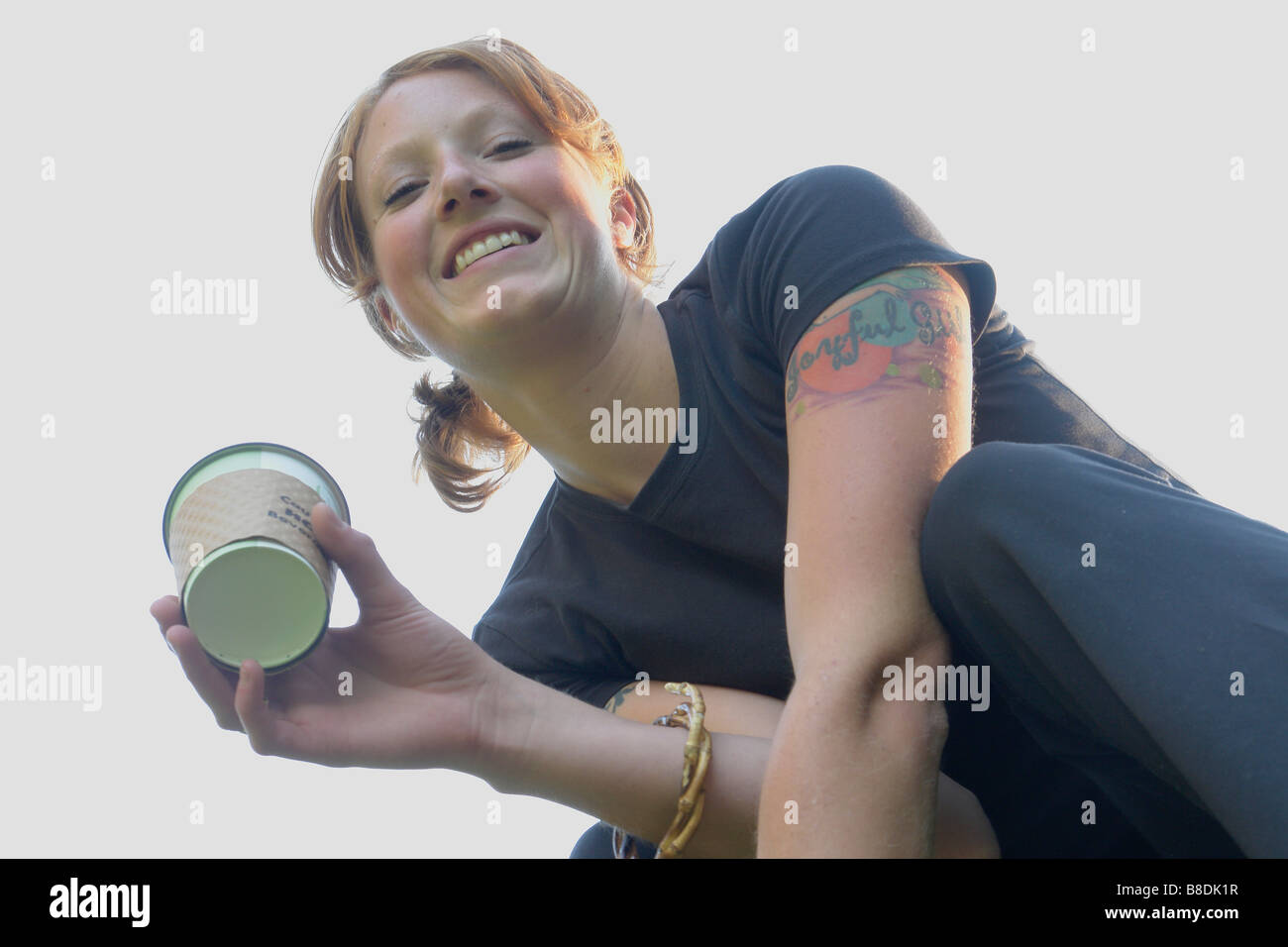 Low angle portrait of woman holding corn-based compostable coffee cup Stock Photo