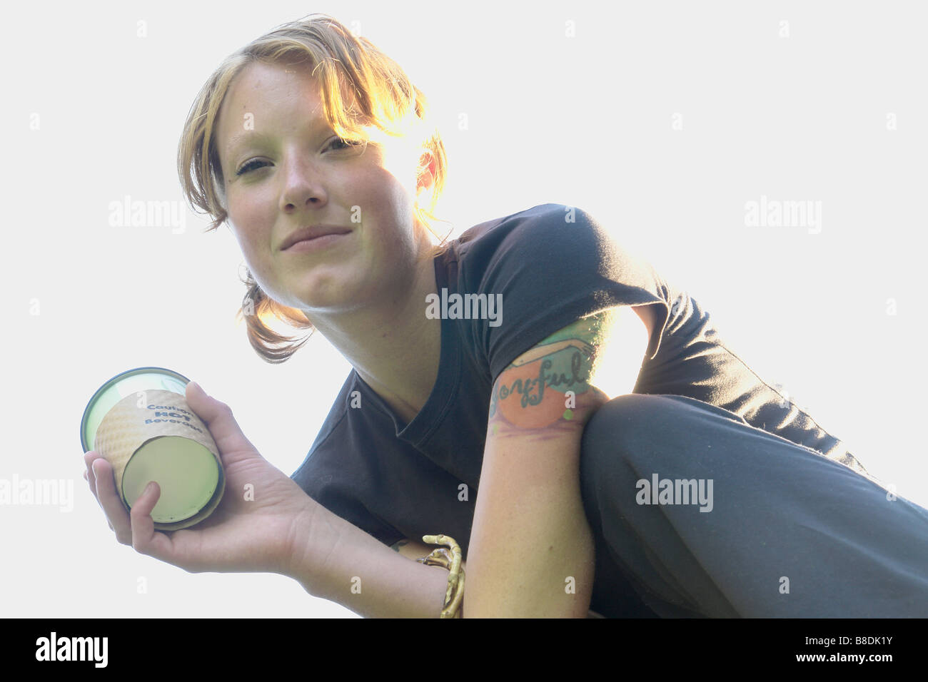 Low angle portrait of woman holding corn-based compostable coffee cup Stock Photo