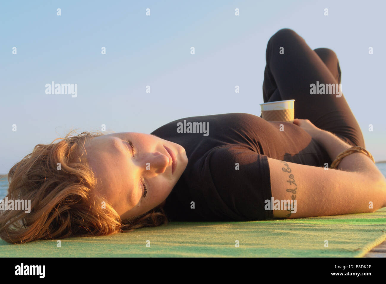 Woman lying on dock by lake, Clear Lake, Riding Mountain National Park, Manitoba, Canada Stock Photo