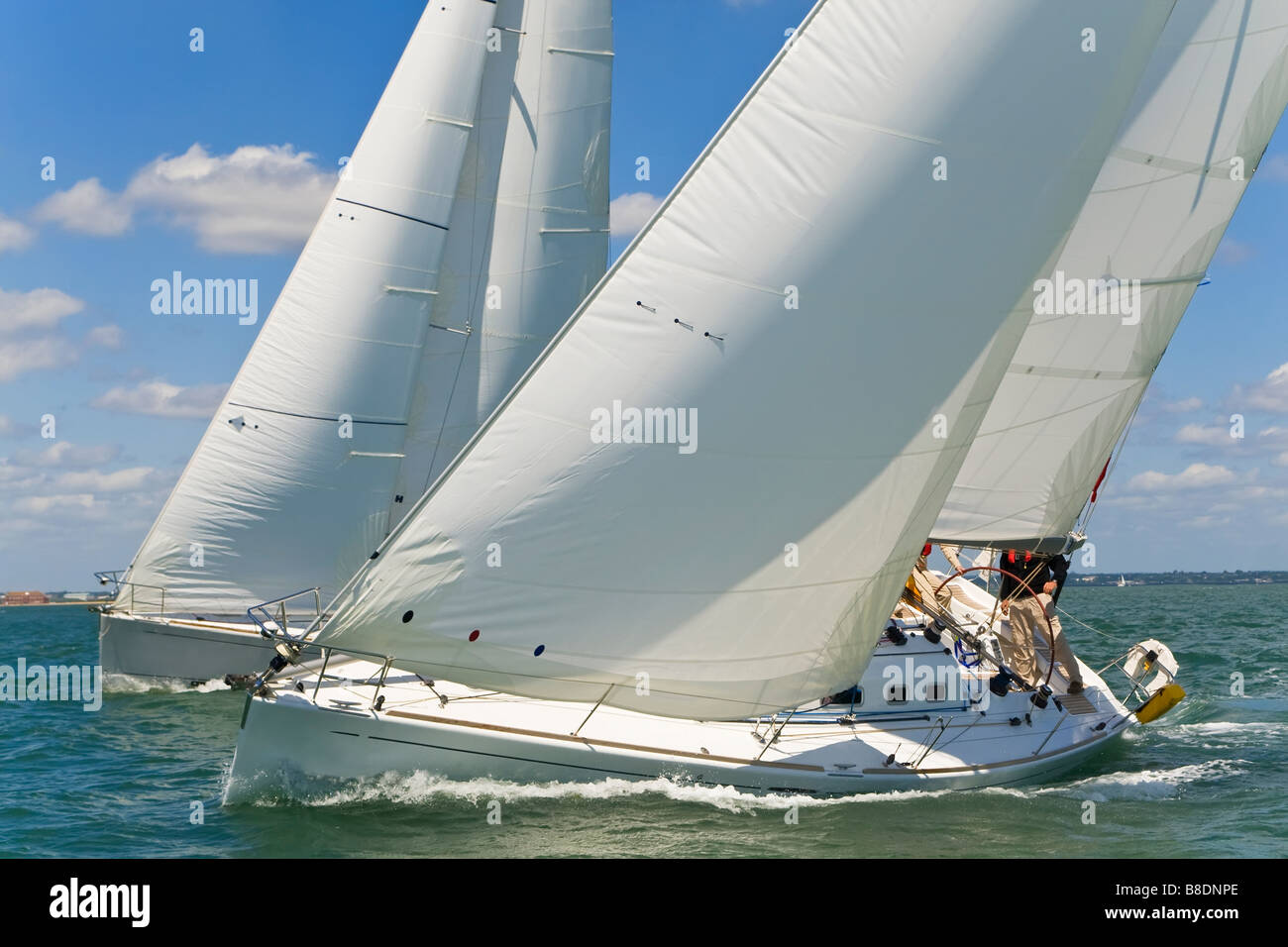 Two beautiful white yachts racing close to each other on a bright sunny day Stock Photo