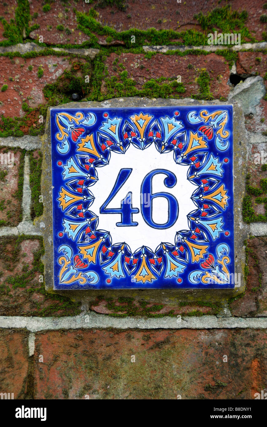 Street number 46 on colourful ceramic tile on brick wall Stock Photo