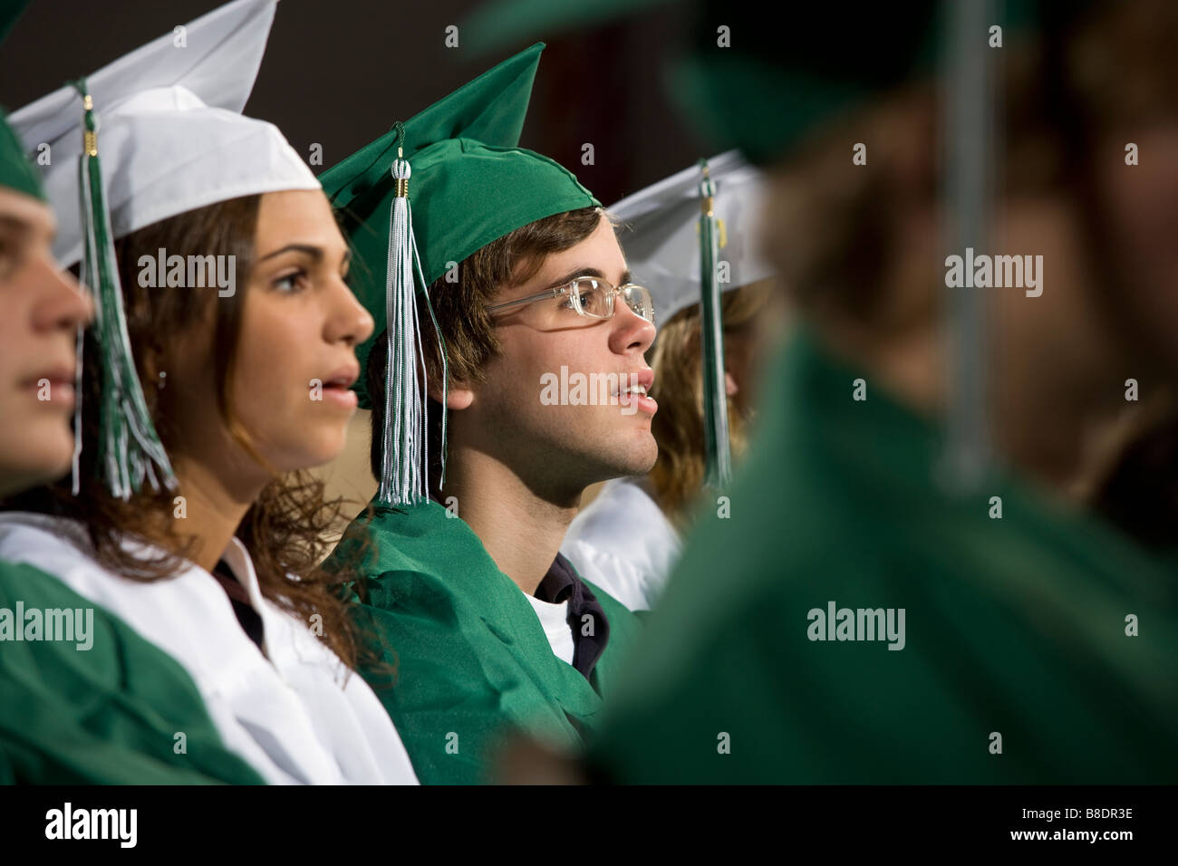 High school students in graduation gowns at commencement ceremony. Stock Photo