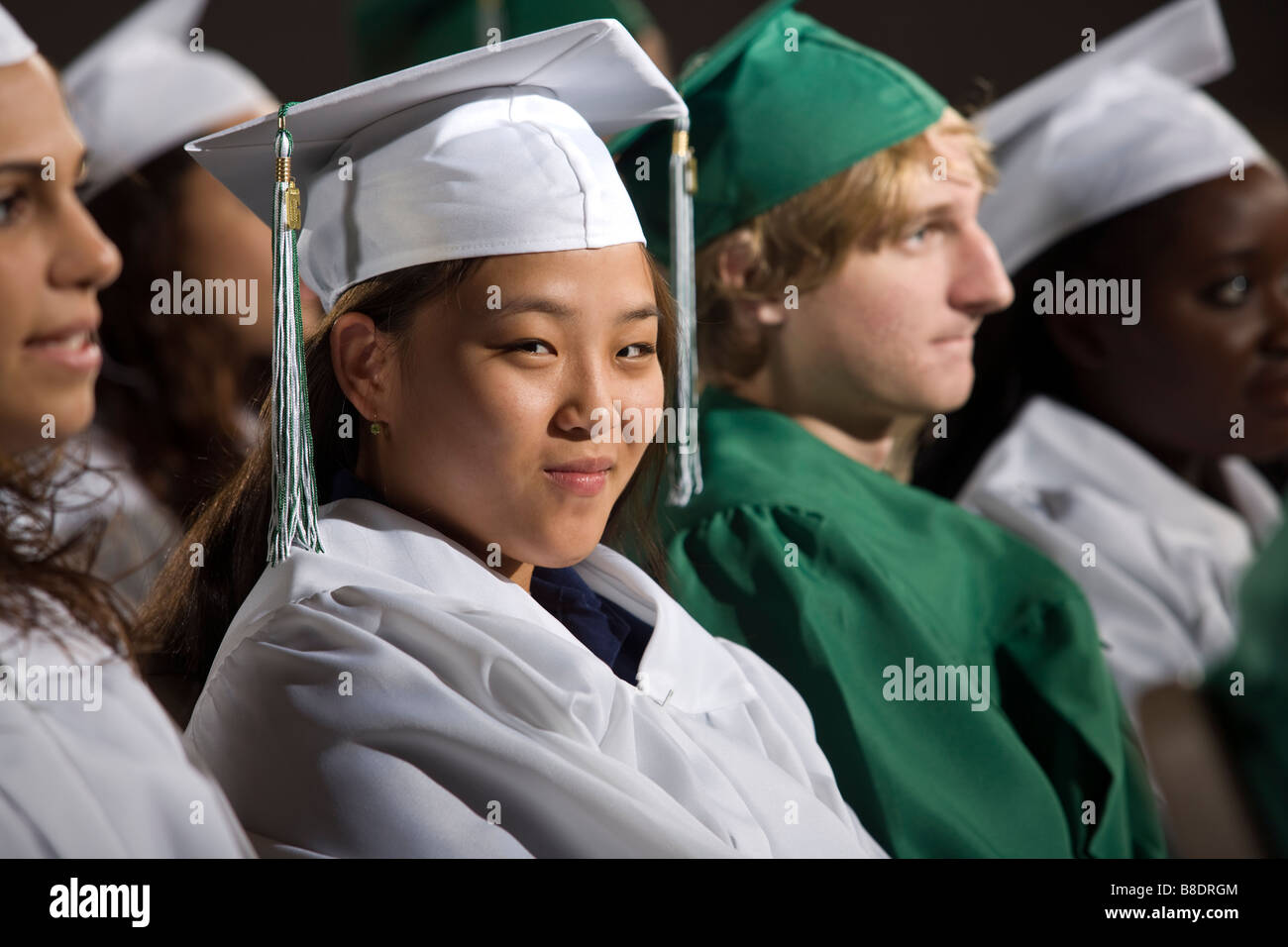 High school students in graduation gowns at commencement ceremony. Stock Photo