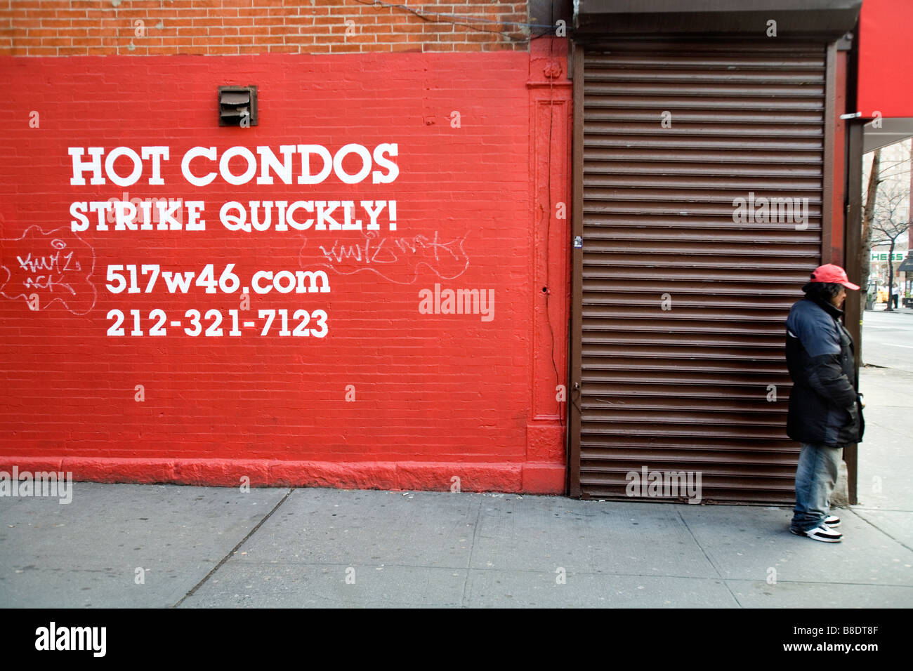 A man standing next to a sign reading 'Hot Condos, Strike Quickly.' Stock Photo