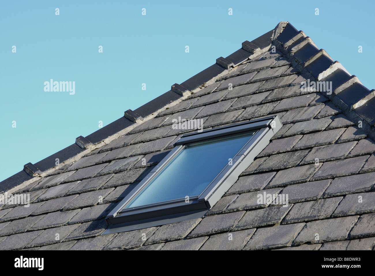 Velux window set into slate roof of house Stock Photo