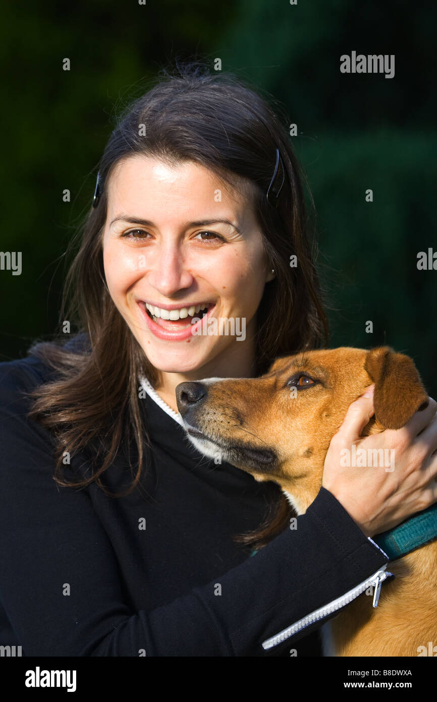 Young caucasian female with brown hair held to a dog with smile looking  happy Stock Photo - Alamy