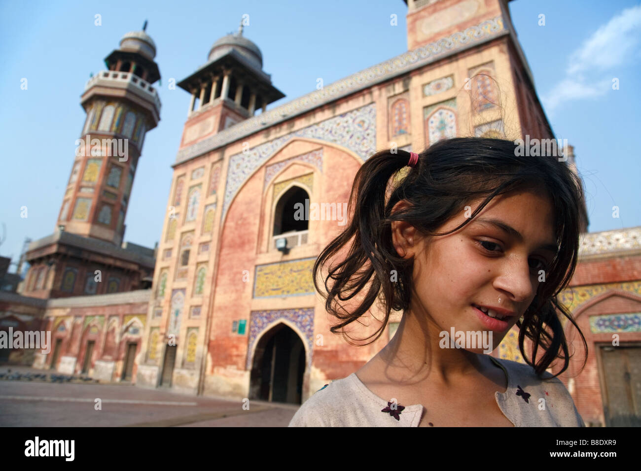 A portrait of a young girl standing in front of the entrance to Wazir Khan Mosque in Lahore, Punjab, Pakistan Stock Photo