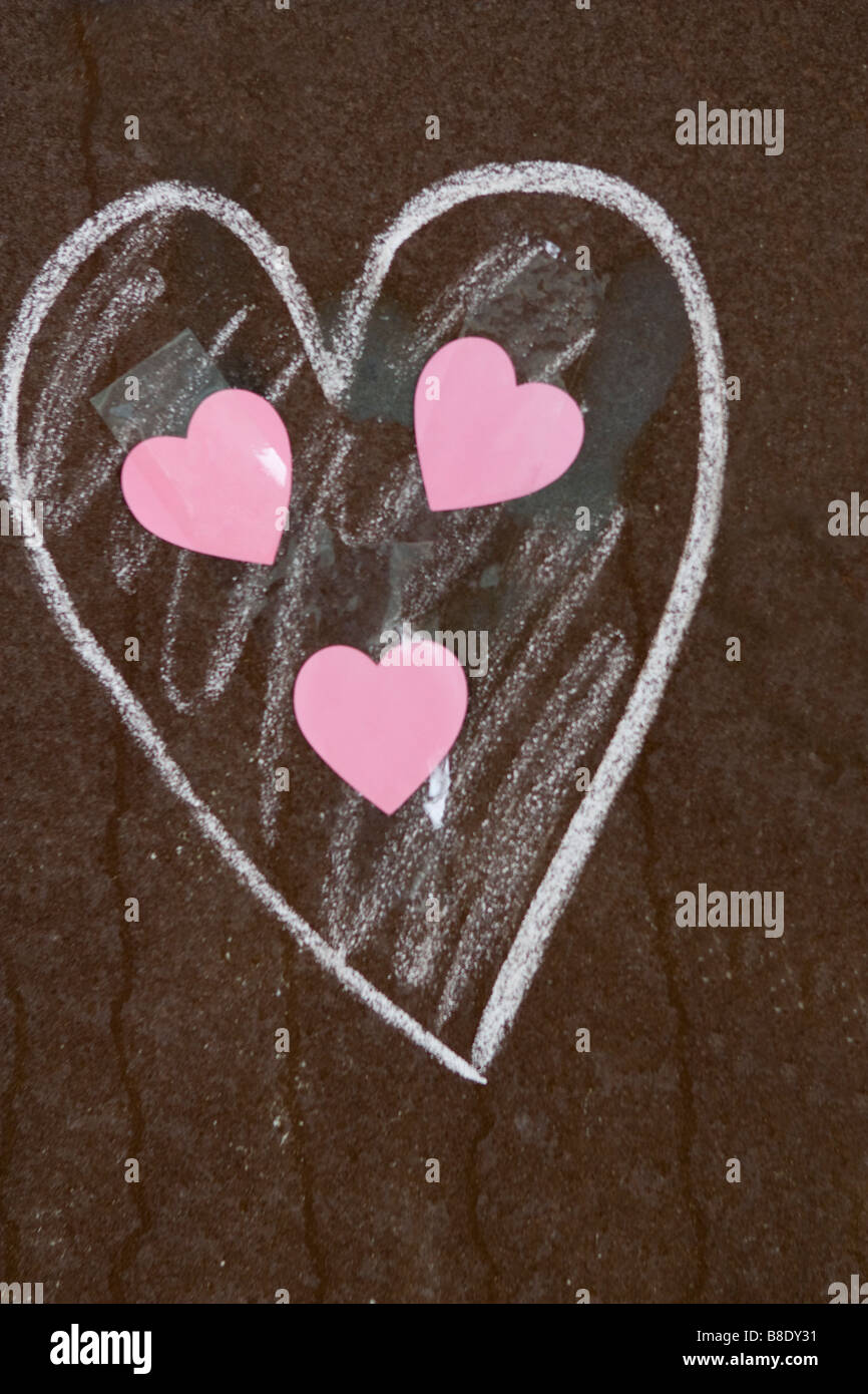 Three pink hearts inside big one painted on rusty metal. Stock Photo