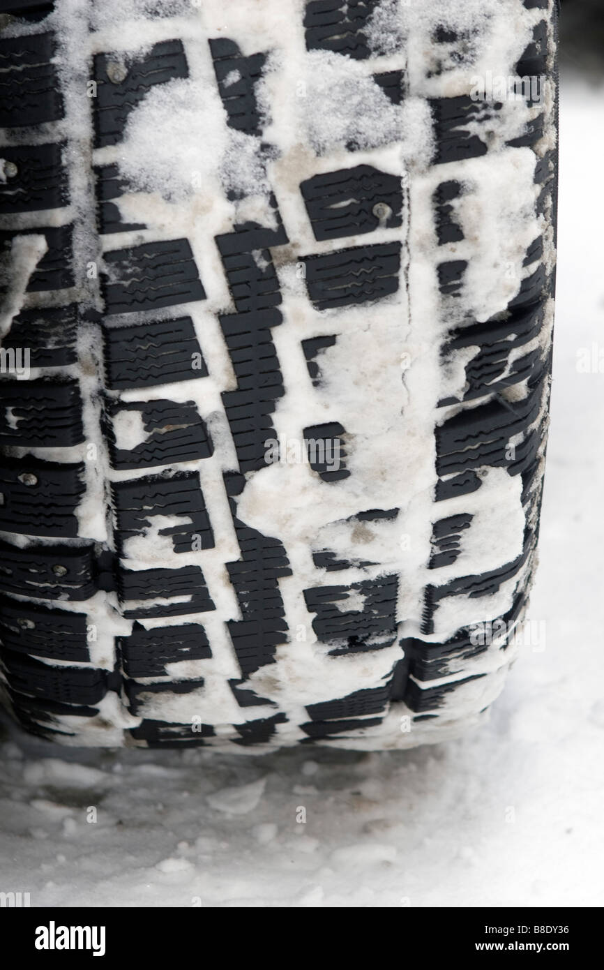 Car snow tyre with studs closeup on snow covered road. Stock Photo