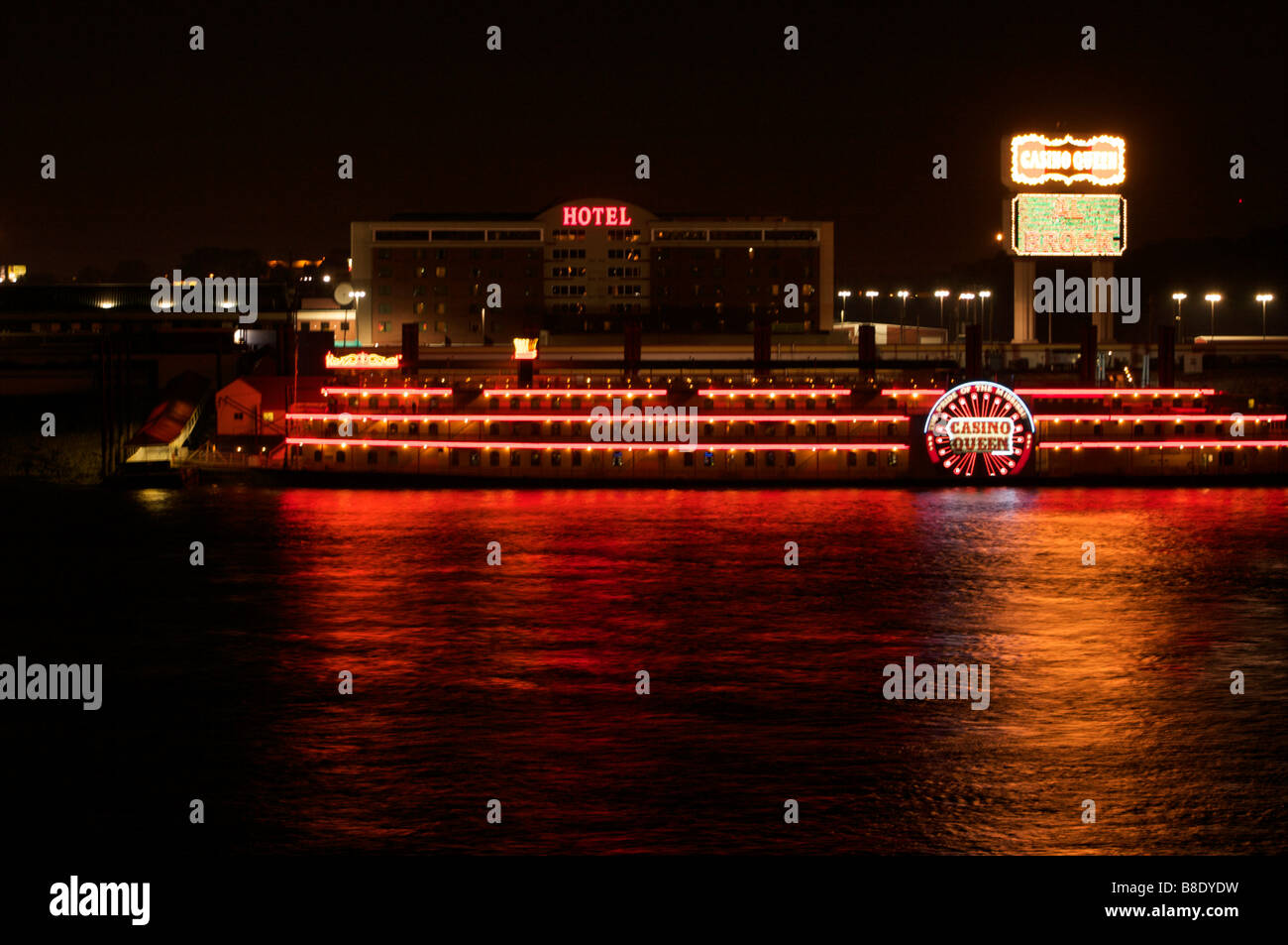 Casino river boat on the Mississippi river in St. Louis Missouri at night with neon lights reflecting on the water with hotel Stock Photo