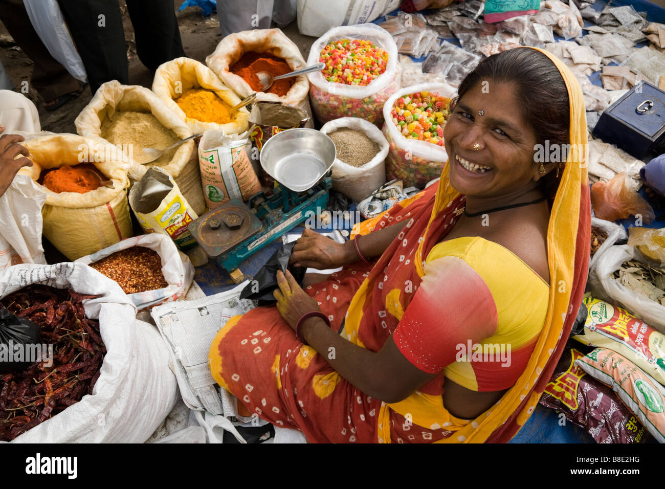 Spices for sale at a street market spice stall, with street seller. Hazira, Surat, Gujarat. India. Stock Photo