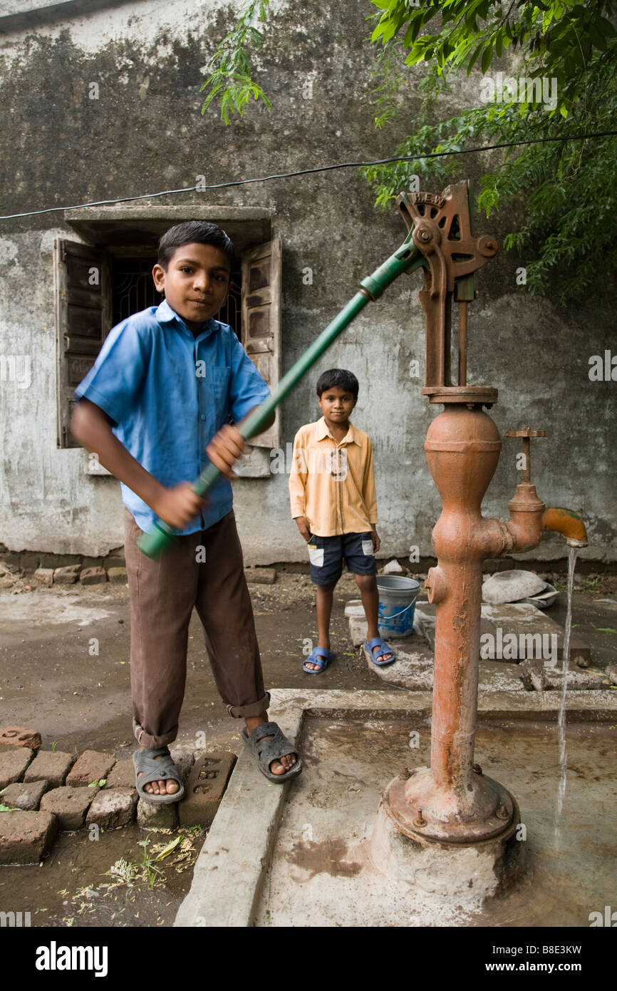 Boy working a hand pump to draw water from a well. Hazira, Surat