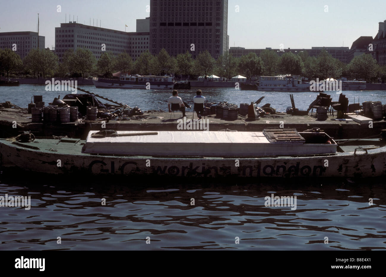 Workers relax in the sun on a London barge proclaiming "Working For London" Stock Photo