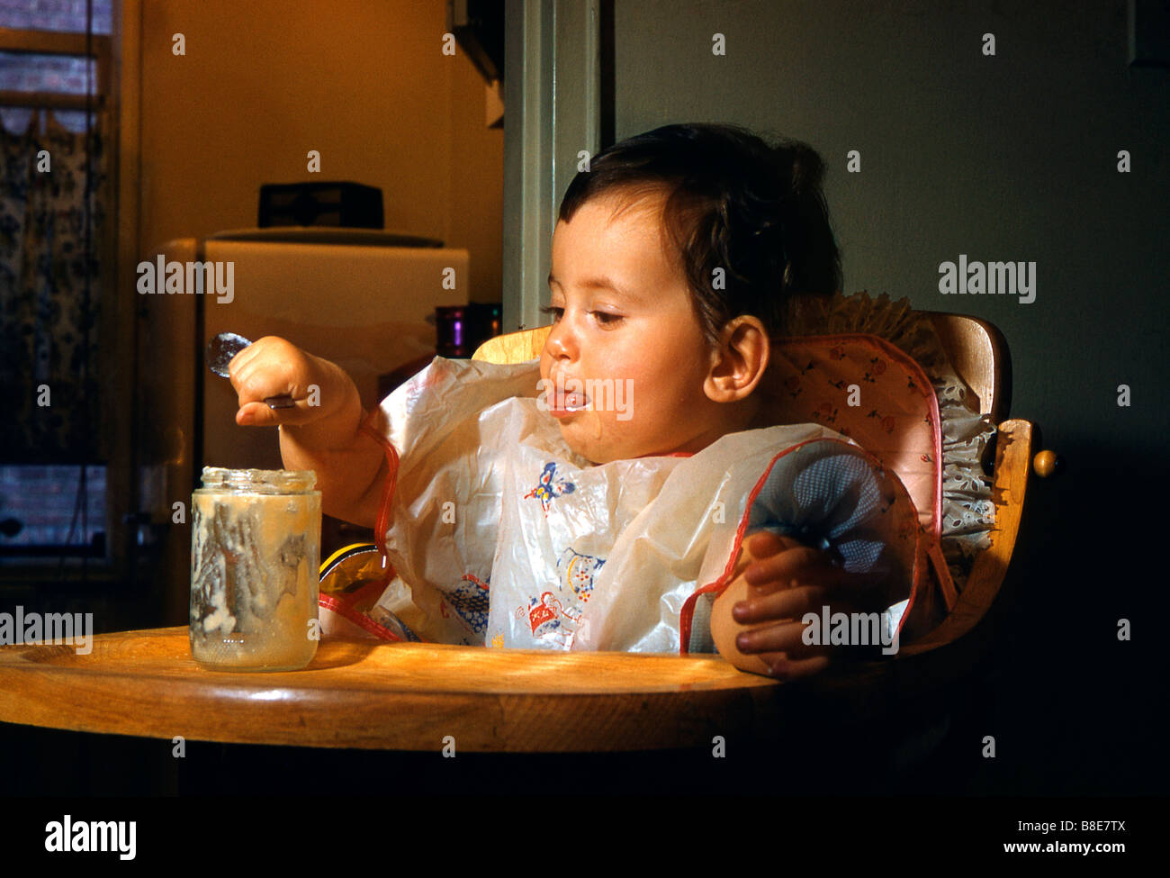 Baby in a high chair enjoying her food, USA, 1955 Stock Photo
