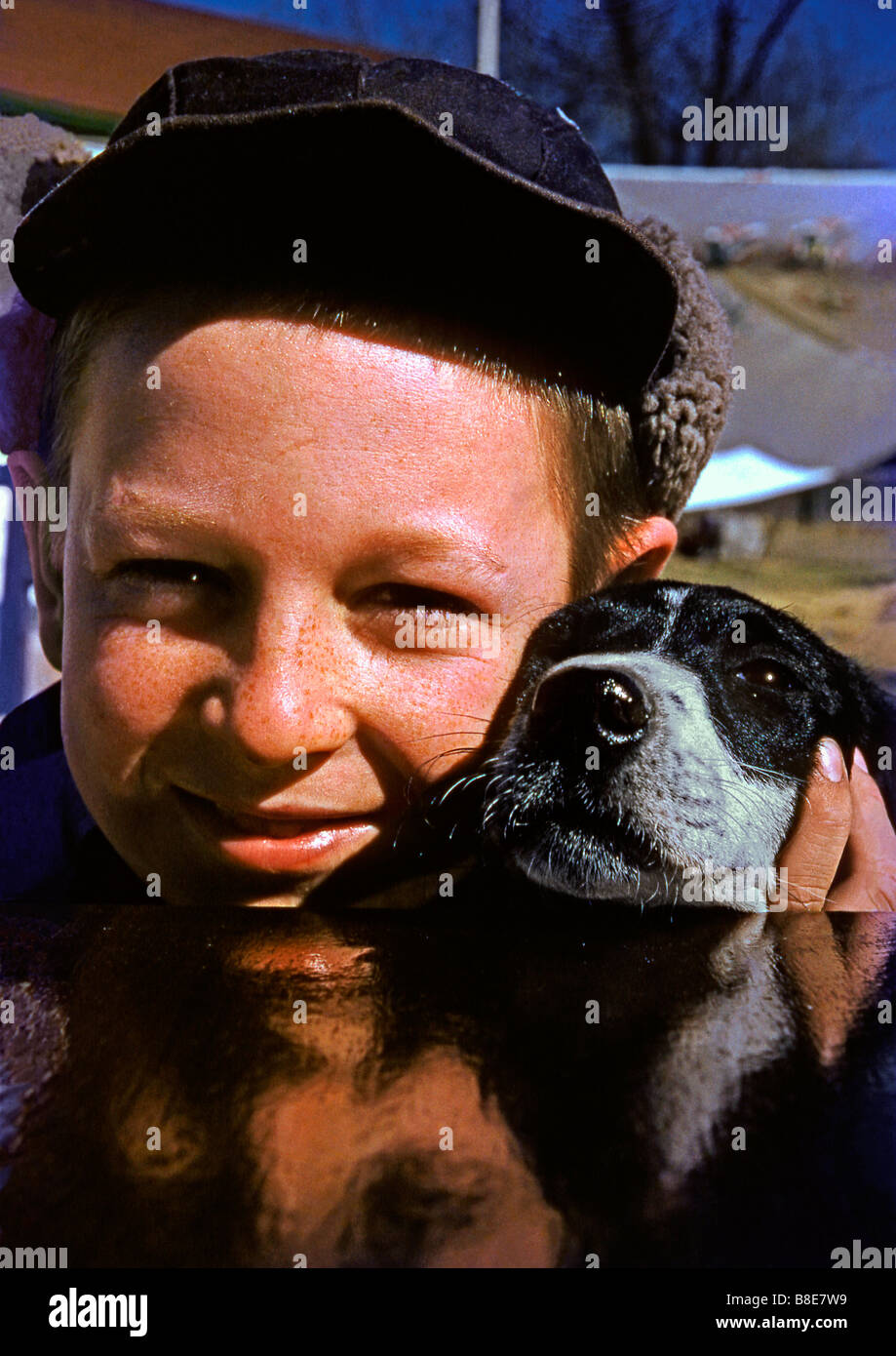 Boy in a winter hat and his pet dog reflected in shiny paintwork of a car, USA, c. 1955 Stock Photo
