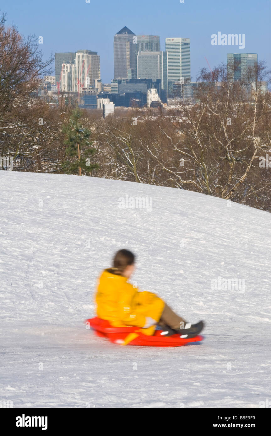 A young girl going downhill on a sled in Greenwich Park on a sunny day