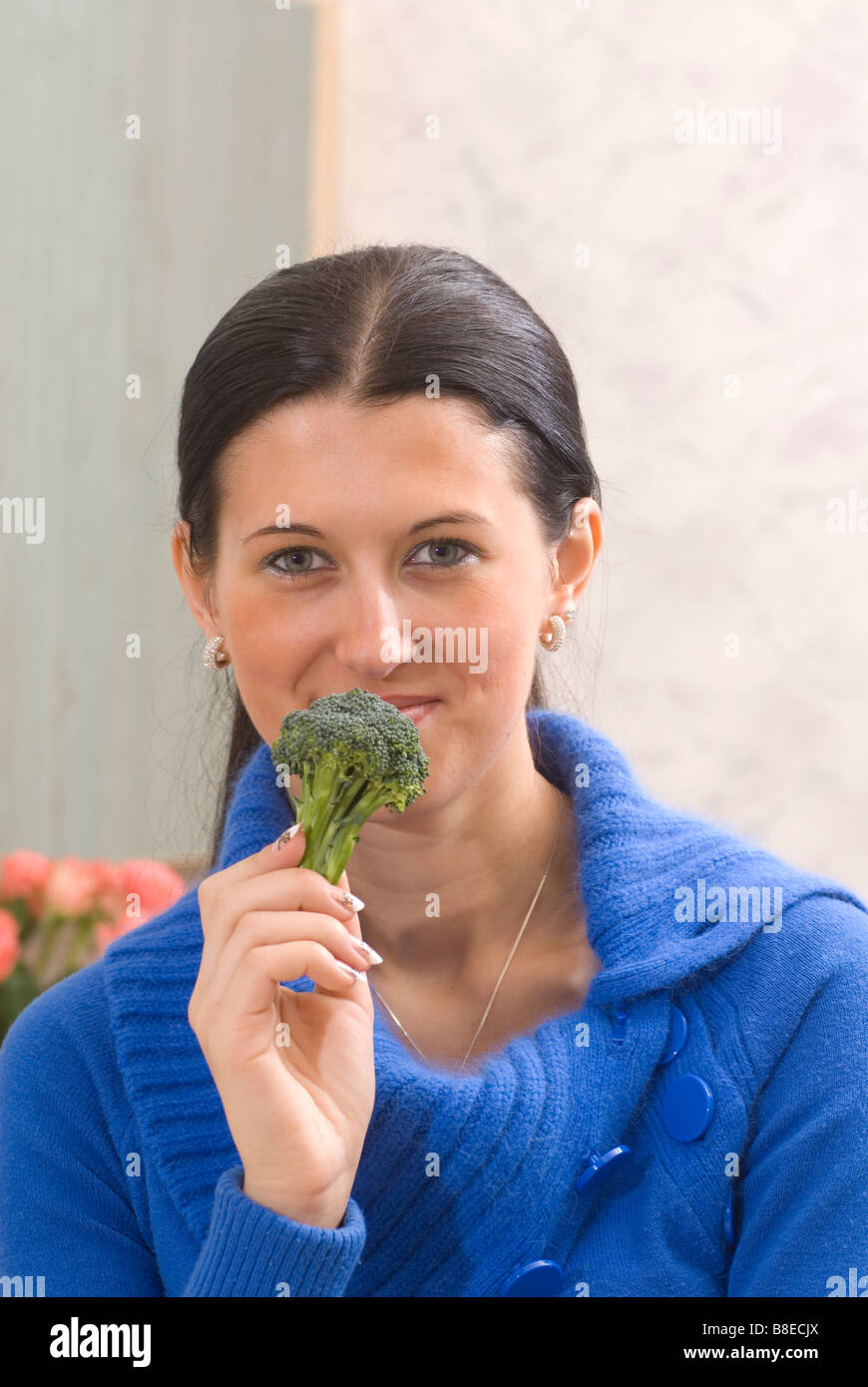 Young woman eating green raw broccoli Stock Photo