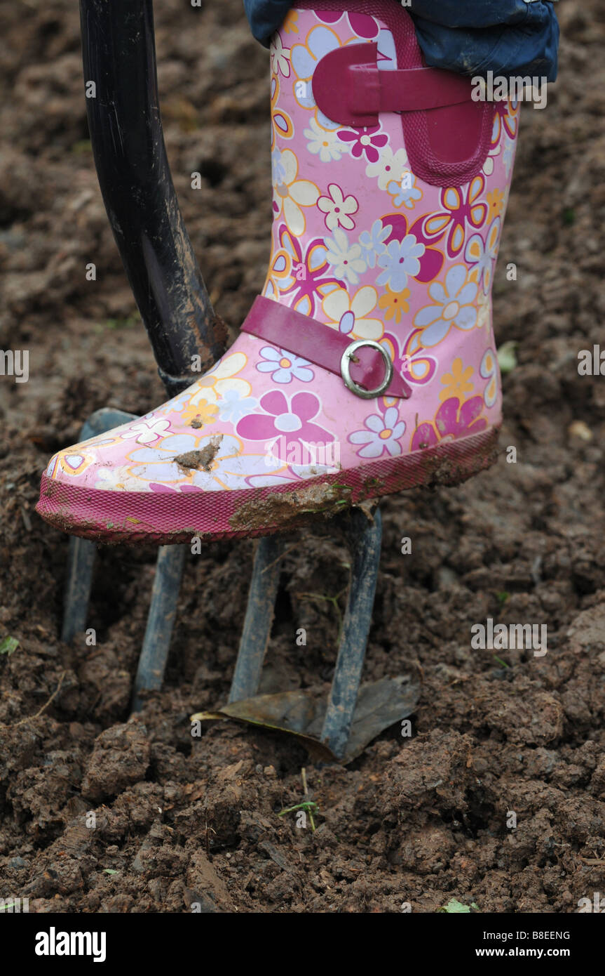 The colourful wellington boots of a school child digging up vegetables in the vegetable plot at a Herefordshire primary school Stock Photo