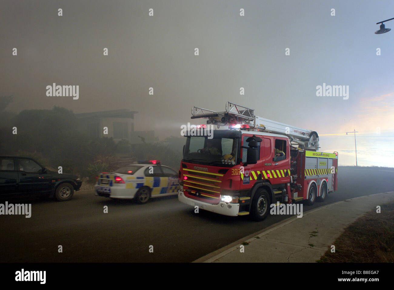 fire truck passes a police car as it arrives at the scene of a major bushfire in New Zealand Stock Photo