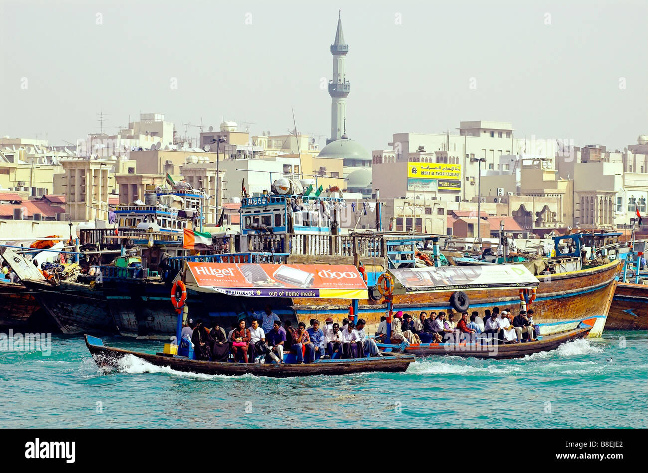 Water taxis taking workers across The Creek, Dubai with  traditional freight boats Dhows Stock Photo