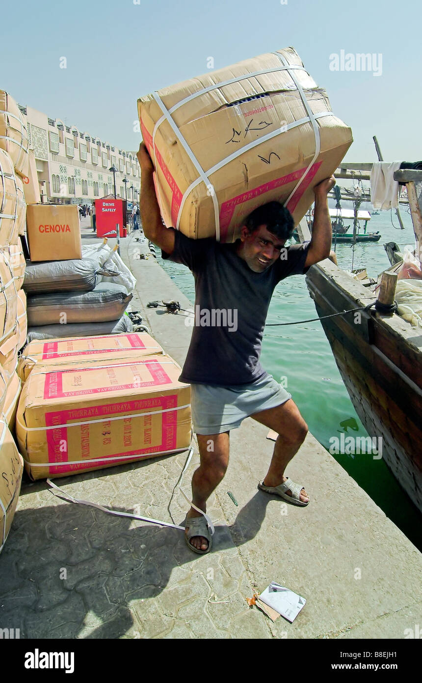 Man loading supplies onto traditional freight boats Dhows The Creek, Dubai Stock Photo