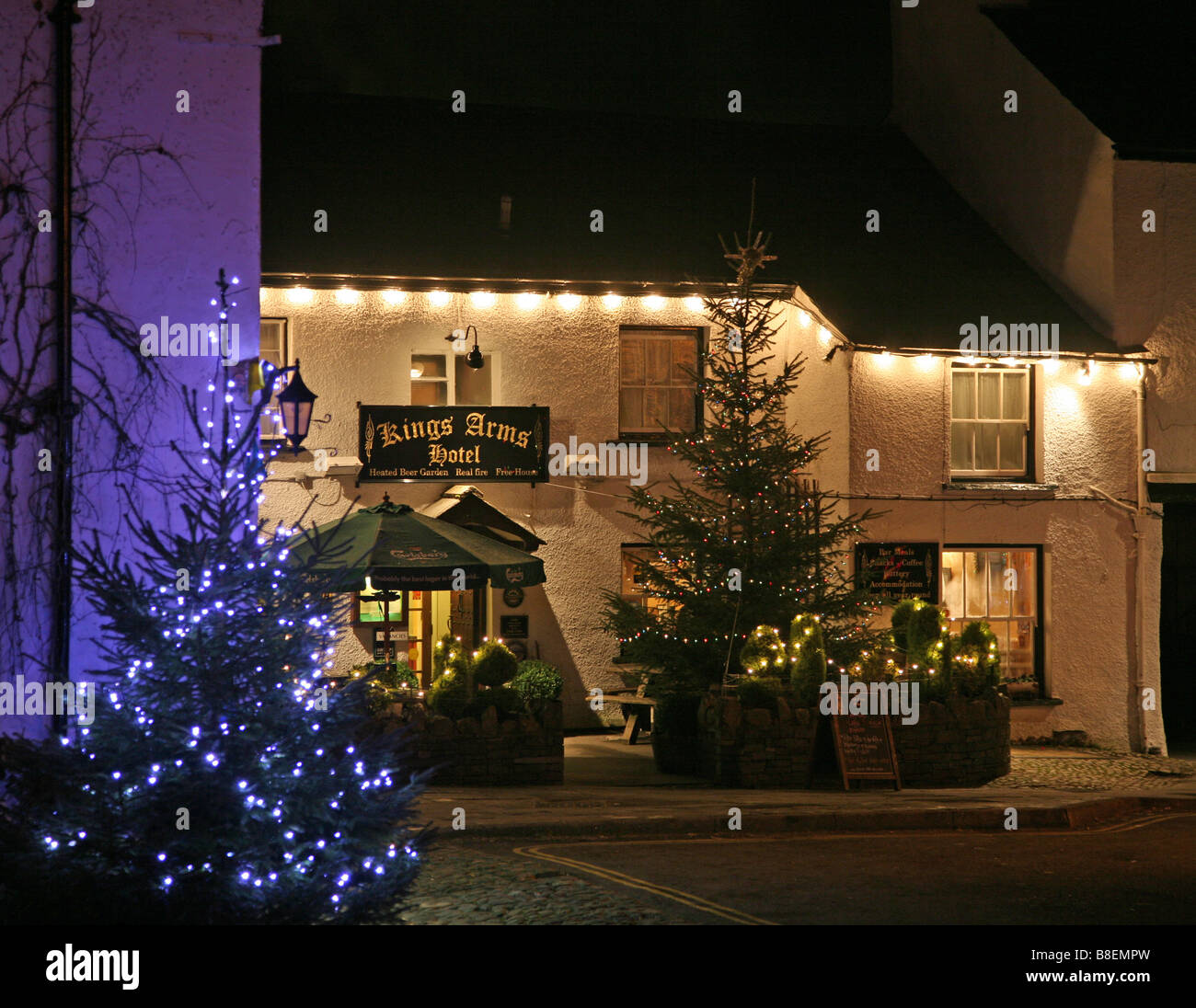 King's Head pub and Hotel, Hawkshead, Lake District at Christmas time with two Christmas trees lit up with decorated lights Stock Photo