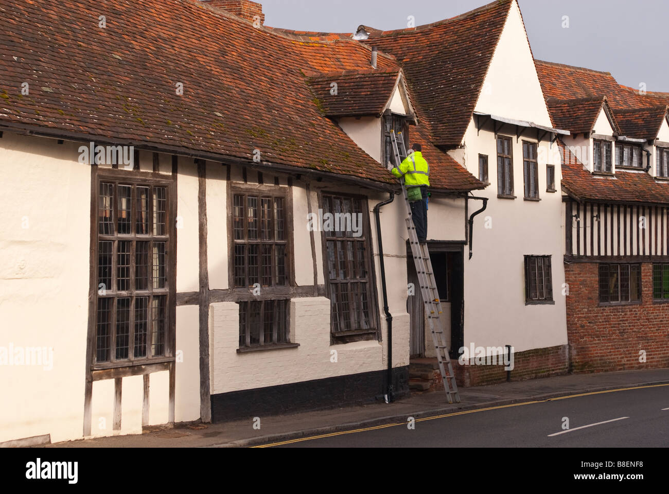 A window cleaner at work up a ladder wearing a high visibility coat in