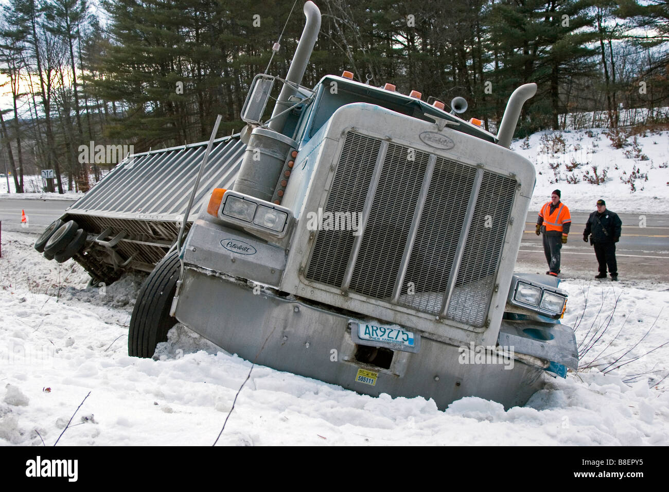 Semi truck in ditch in snow with men looking on Stock Photo Alamy