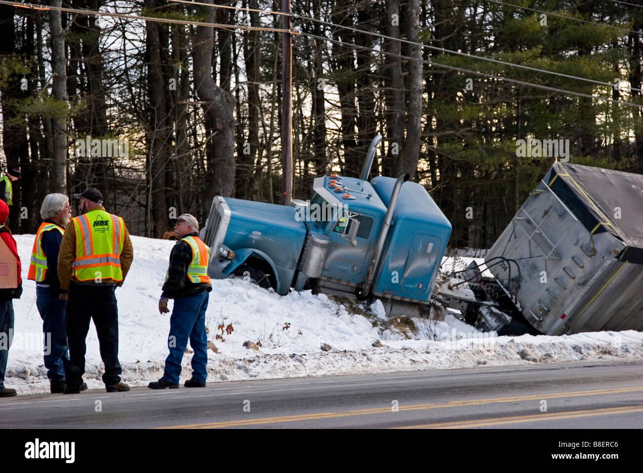 Semi truck in ditch in snow with men looking on Stock Photo