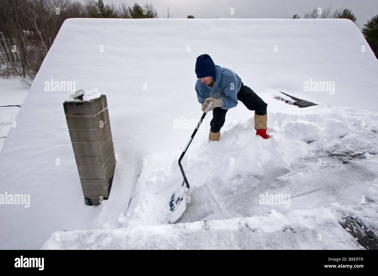 Man shoveling snow off a rooftop in winter Stock Photo Alamy
