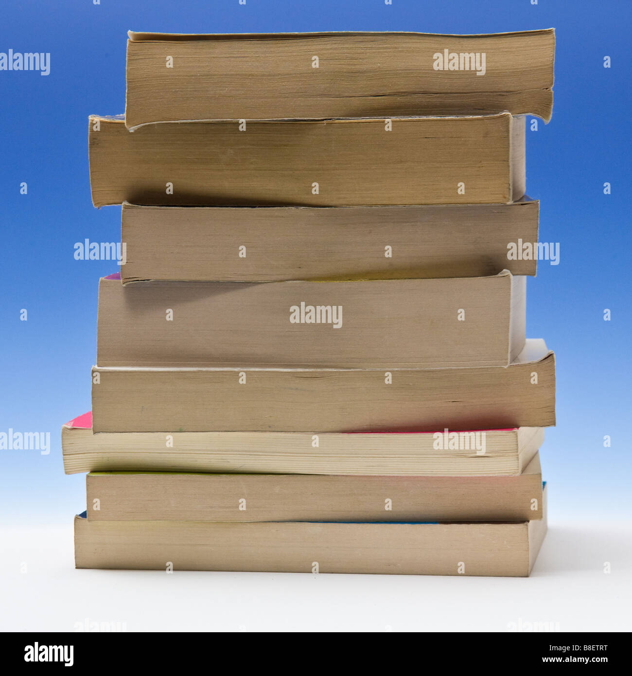 Stack of paperback books on a blue studio background. Stock Photo