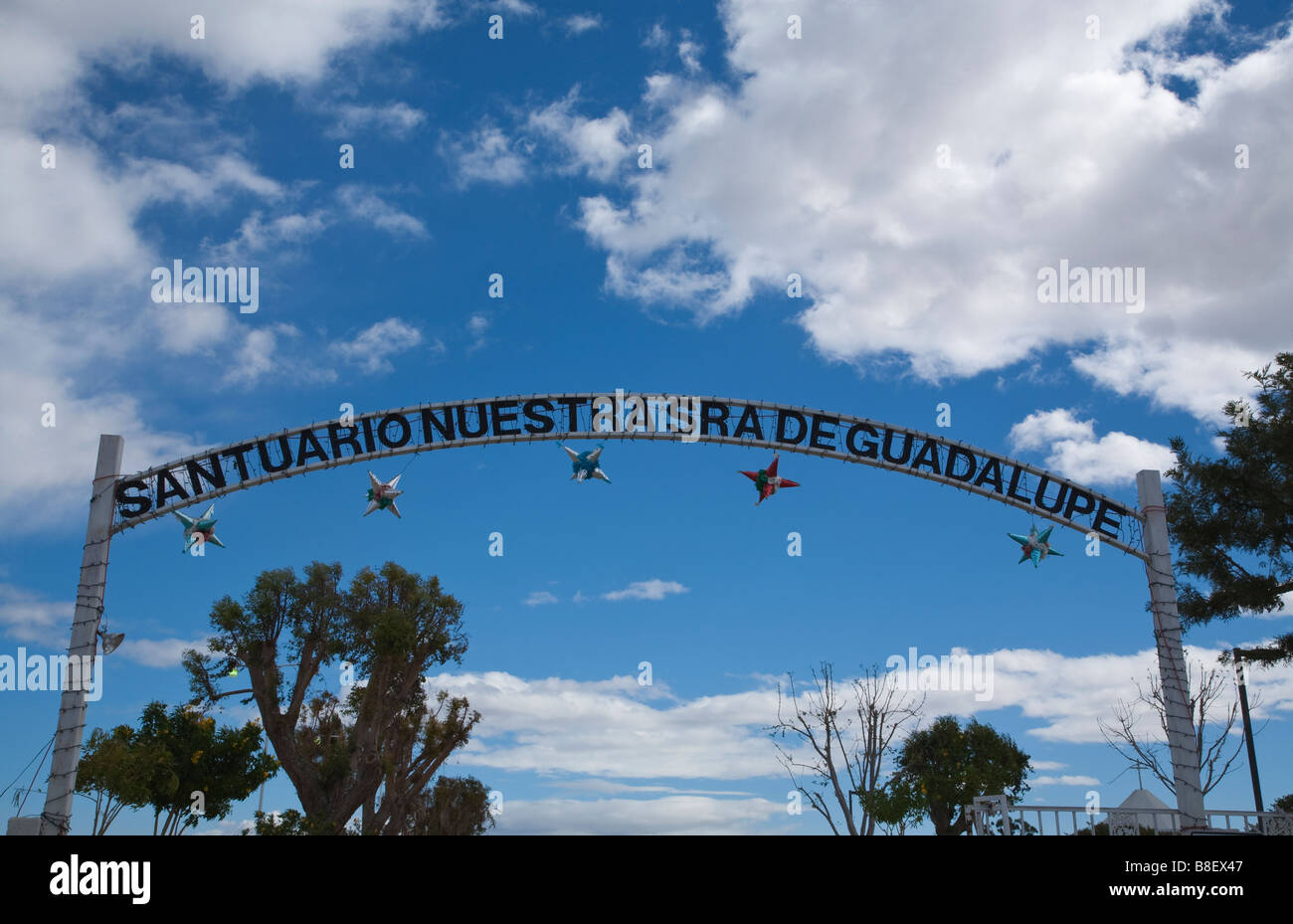 The entrance sign over the Santuario Nuestra Señora de Guadalupe Mecca CA against a deep blue sky with white clouds Stock Photo