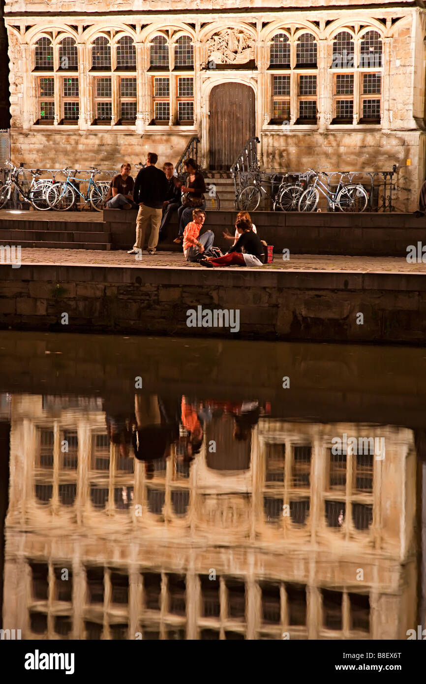 Group of young people talking on waterfront promenade Graslei at night Ghent Belgium Stock Photo