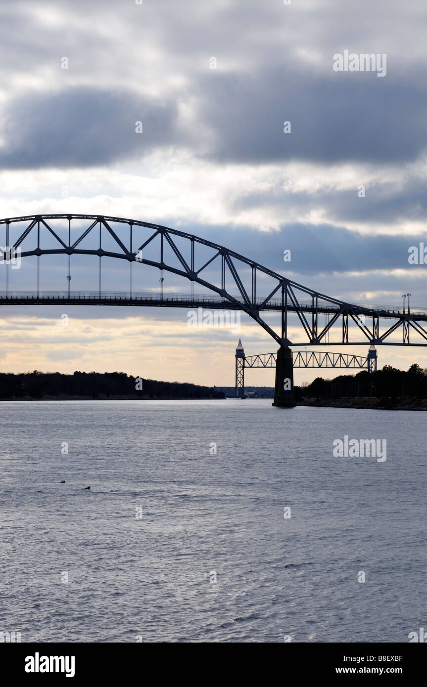 The 'Bourne Bridge' and the 'Cape Cod Canal Railroad Bridge' spanning the 'Cape Cod Canal' on a grey gloomy day. Stock Photo